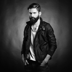 Wall Mural - Portrait of handsome man with beard and mustache. Close-up image of serious brutal bearded man on dark background. Black and white photography