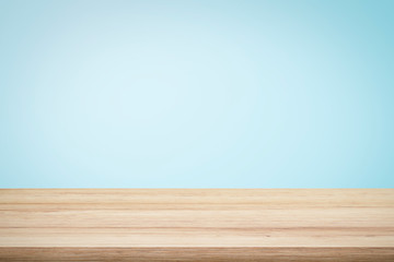 empty wooden deck table over light blue wallpaper background for present product.