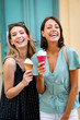 Two young women friends having fun and eating ice cream outdoor