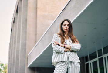 Wall Mural - Stylish confident woman posing outdoors in city street background.