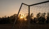 Fototapeta  - Football goal with sunset light background in the public stadium.