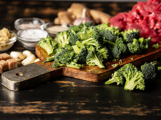 Cooking meat and vegetables broccoli by asian recipe with garlic, ginger and spices. Close up. Cooking recipe concept on wooden background.