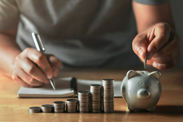 saving money with hand putting coins in piggy bank concept financial