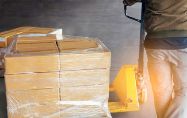 Poster - Worker is working with hand pallet truck unloading shipment goods in warehouse, cargo export, delivering  shipment package boxes