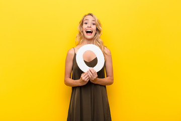 young blonde woman surprised, shocked, amazed, holding the letter P of the alphabet to form a word or a sentence.