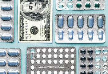 Wall Mural - white and blue pills in blister with money dollar on a blue background, medicine flat lay