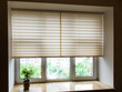 Pleated blinds XL beige color, with 50mm fold closeup in the window opening in the interior. Home blinds - modern bottom up privacy shades half raised on apartment windows.