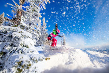 Woman Skier Jumping In Pink Skis On Background Of Blue Sky And Snowy Forest In Mountains, Dust From Snow