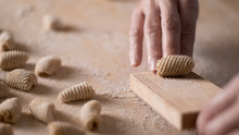 Close Up Process Of Homemade Vegan Gnocchi Pasta With Wholemeal Flour Making. The Home Cook Crawls On The Special Wooden Tool The Gnocco , Traditional Italian Pasta, Woman Cooks Food In The Kitchen