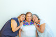 © Emile - Three generations of smiling Mexican women, mother and daughter leaning on grandma, blouses with floral prints on a white background