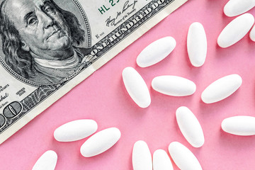 Wall Mural - white pills with money on a pink background, medicine flat lay with copy space, rising cost of health care