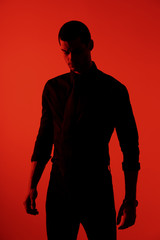 Silhouette of a young confident handsome businessman wearing black shirt in red light