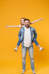 Smiling bearded man with child baby girl. Father little kid daughter isolated on yellow background. Love family parenthood childhood concept. Give piggyback ride to joyful sit on back spreading hands.