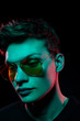 Portrait of a fashion trend male model neon gel light in studio on a dark black background
