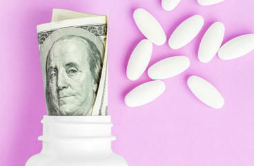 Wall Mural - Roll of money Bills in white pill bottle with white pills. The High Cost of Health Care. Pills and US Currency in Pill Bottles