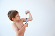 © ruslanshug - funny healthy little caucasian boy measuring his strong muscle using tape on white backgroun with copy space