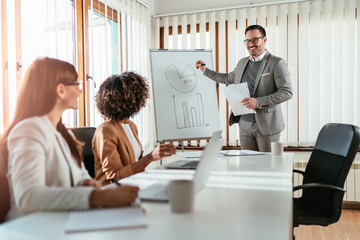 Wall Mural - Cheerful businessman talking to his colleagues on presentation