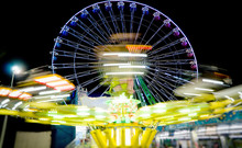 Hurricane Ride And Ferris Wheel In The City Amusement Park At Evening.