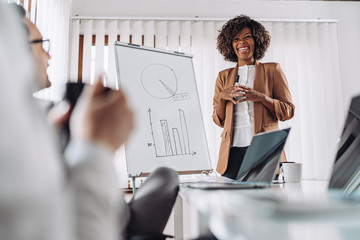 Cheerful businesswoman standing at the office and talking with colleagues