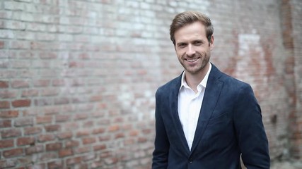 Wall Mural - happy casual man standing with hands in pockets in the middle of a street and looks at the camera