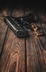 Wall Mural - Modern black gun and ammunition  on a wooden background. Pistol. Weapons for sport and self-defense lie on the table.