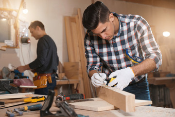 Sticker - Professional carpenter and colleague working with wooden plank in workshop