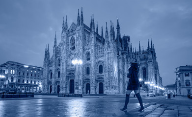 Wall Mural - Woman in black clothes with black hat is walking on the street - Duomo di Milano (Milan Cathedral) and Piazza del Duomo in the Morning, Milan, Italy