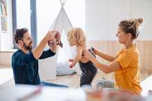 Young Family With Small Child Indoors In Bedroom Getting Dressed.