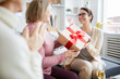 © Seventyfour - Portrait of three cheerful women celebrating birthday at home focus on young woman holding gift box, copy space