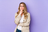 Fototapeta Konie - Young caucasian woman isolated on purple background yawning showing a tired gesture covering mouth with hand.