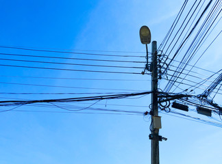 An electric pole with wire, light bulb, and surveillance camera onder clear blue sky