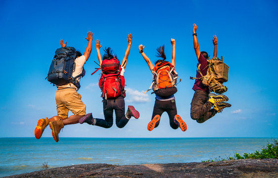 Fototapete - Group of people jumping on mountain top cliff edge. Happy traveler jumping with backpack travel lifestyle adventure concept. Active summer vacations outdoor on mountains success and fun