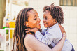 Happiness and joyful  black race african family concept with mother and son together having fun and laughing a lot - hug and love - afro people with dreadlocks hair style - trendy family