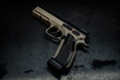 © solidmaks - Modern brown gun on a dark background. Pistol. Weapons for sport and self-defense lie on the table.