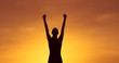 Strong and confident woman raising her fist up to the sunset sky. People power, and winning concept. 