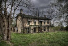 Old Abandoned Farmhouse In The Midwest Surrounded By Leafless Trees And Overgrown Lawn