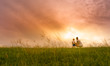 © kieferpix - Mother and son spending time together outdoors watching the beautiful sunset in a grass field.