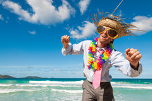 Office Worker On Vacation Wearing Sunglasses, Tourist Straw Hat And Lei Dancing On A Tropical Beach
