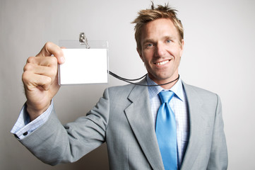 Cheerful businessman smiling as he holds up his blank name tag