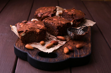 Brownie, Chocolate cakes with almonds on a wooden board, sprinkled with cocoa. Served homemade cakes. Top view. Free space for text.