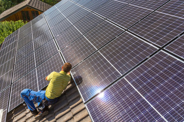 Installing solar photovoltaic panel system. Solar panel technician installing solar panels on roof. Alternative energy ecological concept.