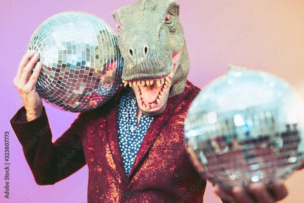 Senior man having fun wearing t-rex mask in discotheque - Elegant dinosaur masquerade male celebrating carnival party inside disco club - Funny absurd holidays and crazy people humor lifestyle concept - obrazy, fototapety, plakaty 