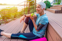 Portrait Of A Beautiful Older Woman With Green Healthy Food After Workout. Portrait Of Fit Mature Woman Smiling While Holding An Apple And Bottle Of Water. Sporty Senior Woman
