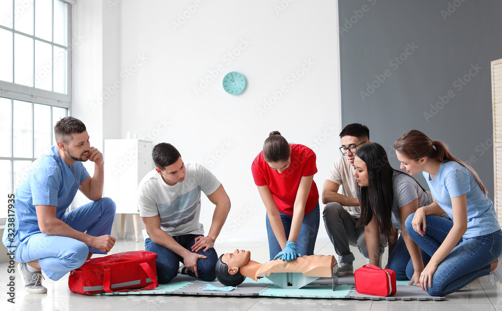 Instructor demonstrating CPR on mannequin at first aid training course - obrazy, fototapety, plakaty 