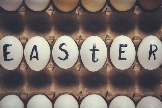 Easter festive eggs in carton with text. Easter text written on white eggs. Happy easter, spring festive holidays concept on the colorful background