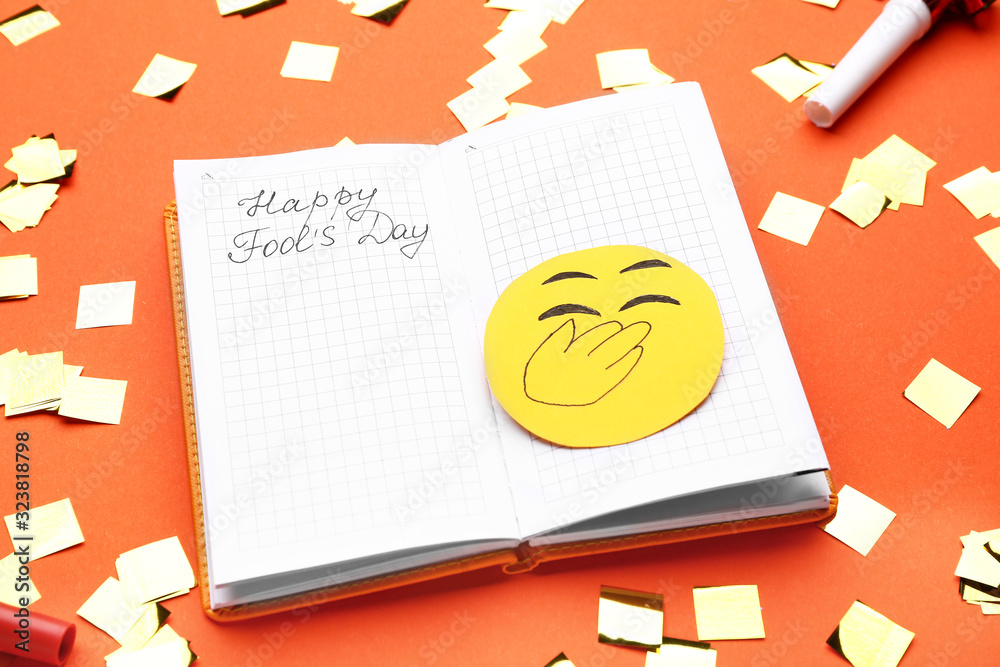 Notebook with text HAPPY FOOL'S DAY on color background