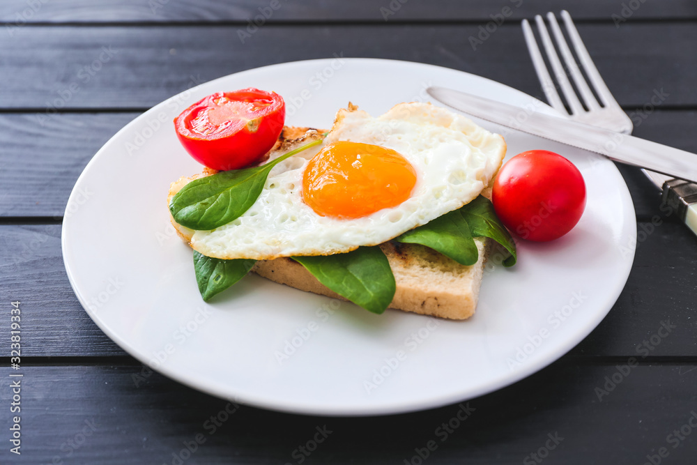 Tasty fried egg with toasted bread and tomatoes on plate