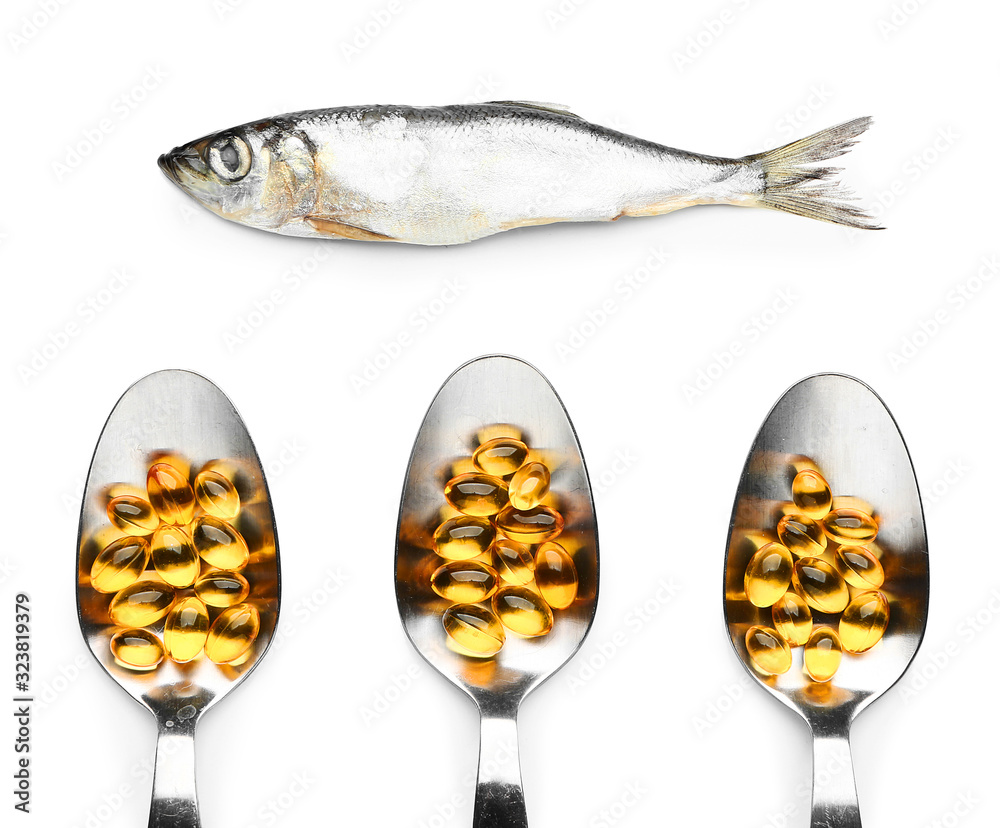 Fish and spoons with oil pills on white background