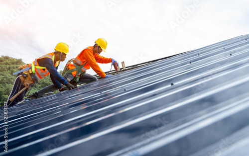 Roof repairman working on the working at height.Professional industrial climber in helmet and uniform works at height,Industrial climbing at construction site,Working at height equipment concept.