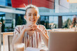 © Strelciuc - A smiling caucasian student with freckles is resting at the computer in a coffee bar in a sunny summer day